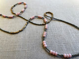 closeup view of gemstone bead necklace comprising pink opal, grey pyrite and bronze.