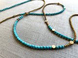 closeup view of gemstone bead necklace comprising turquoise, gold hematite and bronze dot accents.