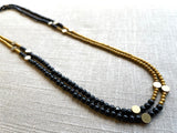top view of gemstone bead necklace comprising black onyx, gold hematite and bronze dot accents.