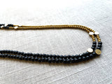 side view of gemstone bead necklace comprising black onyx, gold hematite and bronze dot accents.