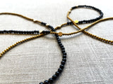 closeup view of gemstone bead necklace comprising black onyx, gold hematite and bronze dot accents.