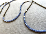 closeup view of gemstone bead necklace comprising periwinkle iolite, light gold hematite and bronze hex accents.