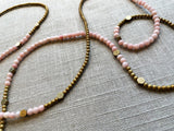closeup view of gemstone bead necklace comprising pink opal, gold hematite and bronze hex accents.