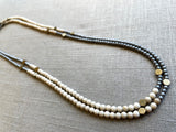 top view of gemstone bead necklace comprising off-white fossil jasper, silver hematite and bronze hex accents.