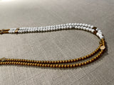side view of gemstone bead necklace comprising white howlite, gold and silver hematite and bronze hex accents.
