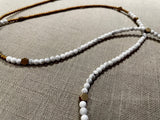 closeup view of gemstone bead necklace comprising white howlite, gold and silver hematite and bronze hex accents.