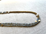 sideview of gemstone bead necklace comprising grey labradorite, gold and silver hematite and bronze dot accents.