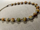 side view of gemstone bead necklace comprising blue/brown calcite, gold and silver hematite.
