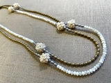 top view of gemstone bead necklace comprising hand-sewn pearl clusters, white mother of pearl, light gold hematite and silver hematite.