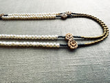 side view of gemstone bead necklace comprising antique hand-carved bone flowers, white pearl and gold hematite