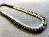 top view of gemstone bead necklace comprising light yellow rutilated quartz, white moonstone and brown exotic wood.
