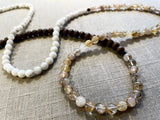 closeup view of gemstone bead necklace comprising light yellow rutilated quartz, white moonstone and brown exotic wood.