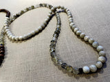 closeup view of gemstone bead necklace comprising green tourmaline, white siberian moonstone and brown exotic wood.
