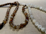 closeup view of gemstone bead necklace comprising peach moonstone, white moonstone and brown exotic wood.