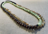 top view of gemstone bead necklace comprising green calcite, light yellow rutilated quartz and brown exotic wood.