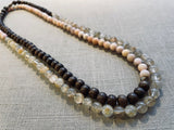top view of gemstone bead necklace comprising pink opal, light yellow rutilated quartz and brown exotic wood.