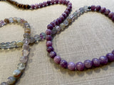 closeup view of gemstone bead necklace comprising purple lepidiolite, green flourite and brown exotic wood.