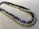top view of gemstone bead necklace comprising purple lepidiolite, green prehnite and brown exotic wood.