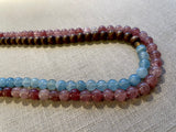 side view of gemstone bead necklace comprising pink strawberry quartz, blue calcite and brown exotic wood.