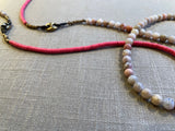 closeup view of gemstone bead necklace comprising pink opal, pink vinyl disk and bronze mariners links.