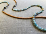top view of gemstone bead necklace comprising blue amazonite, tangerine vinyl disk and bronze mariners links.