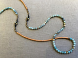closeup view of gemstone bead necklace comprising blue amazonite, tangerine vinyl disk and bronze mariners links.