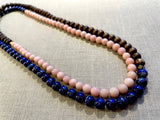 top view of gemstone bead necklace comprising pink opal, blue lapis and brown exotic wood.
