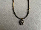 closeup of antique snake pendant hung on metallic bead choker
