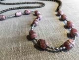 closeup of gemstone bead necklace comprising pink rhodochrosite, grey moonstone, exotic wood and silver hematite Edit alt text