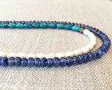 side view of gemstone bead necklace comprising turquoise, beige conch shell and blue sapphire
