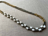 top view of gemstone bead necklace comprising white shell, bronze, dark grey pyrite