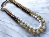 top view of gemstone bead necklace comprising white pearl, neutral rutilated quartz and exotic wood with antler clasp