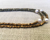 side view of gemstone bead necklace comprising white pearl, bronze and dark grey pyrite