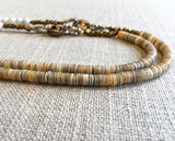 side view of gemstone bead necklace comprising white moonstone, tan shell and bronze mariners link