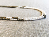 side view of gemstone bead necklace comprising white shell and gold hematite