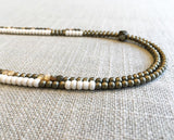 side view of gemstone bead necklace comprising tan shell, white horn and matte light gold