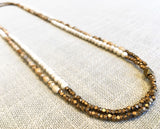 top view of gemstone bead necklace comprising tan landscape jasper, off-white fossil jasper and bronze