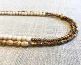 side view of gemstone bead necklace comprising tan landscape jasper, off-white fossil jasper and bronze