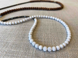 closeup of gemstone bead necklace comprising white moonstone, exotic wood and dark grey pyrite Edit alt text