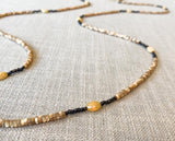 closeup of gemstone bead necklace comprising beige shell, ethiopian opal and dark bronze