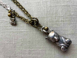 closeup of antique sterling silver bear rattle pendant on chain mix