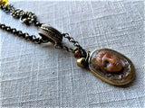 closeup of antique carved Medusa cameo pendant on chain mix