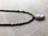 side view of antique cameo pendant hung on metallic bead choker
