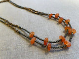 top view of gemstone bead necklace comprising red carnelian, grey pyrite and bronze. 