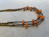 side view of gemstone bead necklace comprising red carnelian, grey pyrite and bronze.