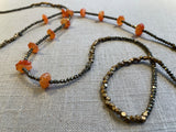 closeup view of gemstone bead necklace comprising red carnelian, grey pyrite and bronze.