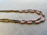 side view of gemstone bead necklace comprising pink opal, grey pyrite and bronze. 