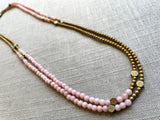 top view of gemstone bead necklace comprising pink opal, gold hematite and bronze hex accents. 