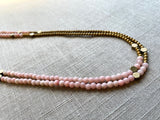 side view of gemstone bead necklace comprising pink opal, gold hematite and bronze hex accents. 