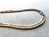 side view of gemstone bead necklace comprising off-white fossil jasper, silver hematite and bronze hex accents. 
